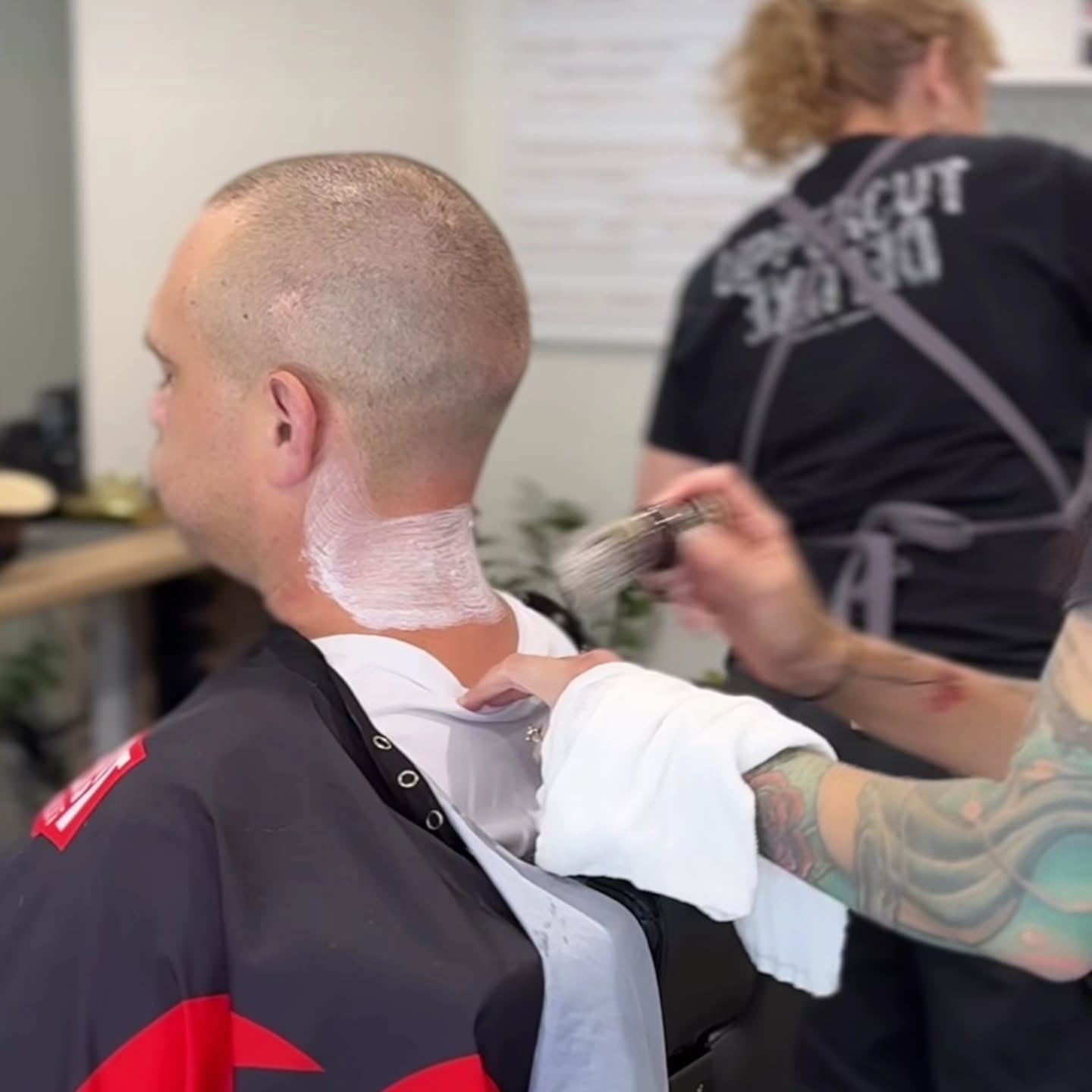 A barber finishing a cut with a hot towel at the back of the neck