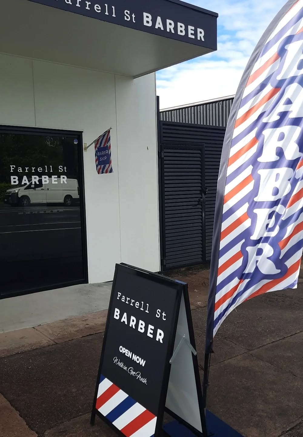 The shopfront from the street, with the barber flag and the open board out